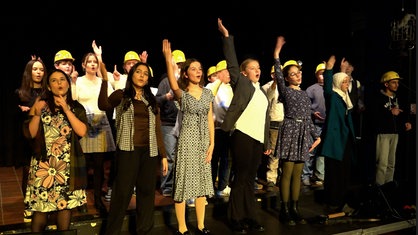 Achtklässler singen im Ensemble auf der Bühne