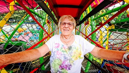 Eine Seniorin in einem Kirmes-Fahrgeschäft, der Affenschaukel