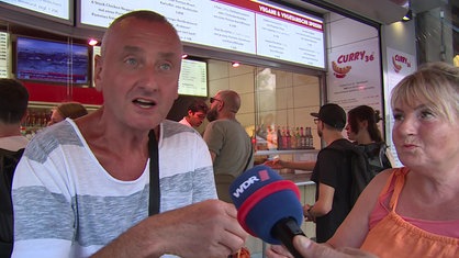 Ein Mann vor einem Imbiss-Restaurant im Interview