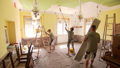 Auf dem Bild sind drei Handwerker zu sehen, die einen der Räume des Landgasthauses neu streichen.