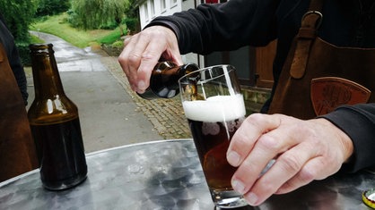 Jemand schenkt Bier in ein Glas ein.