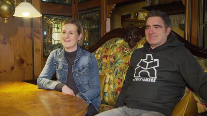 Das Bild zeigt Sarah Heimann und Dirk Teichmann von der Bürgergenossenschaft Darup auf einem Sofa mit Früchte-Muster.