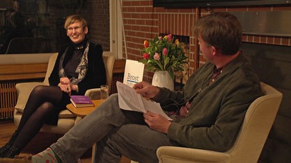 Eva von Redecker und Moderator Friedolin Lingg sitzen auf Stühlen und unterhalten sich