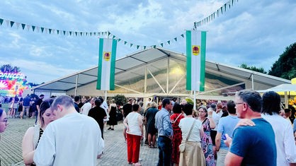 Viele Feiernde vor einer Schützenhalle.