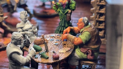 Kleine Figuren sitzen am Tisch und spielen Karten.