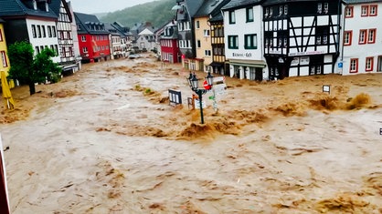 Wassermassen in einer Straße, links und rechts Fachwerkhäuser, ein Schild ist fast komplett unter Wasser