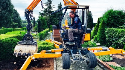 John Reinarz arbeitet mit einem Bagger auf dem Friedhof in Solingen.