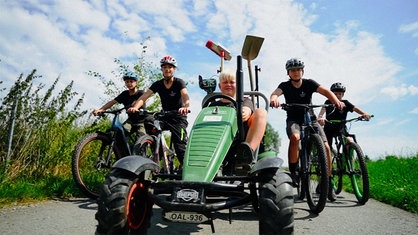 Fünf Jungs auf Fahrrädern und einem kleinen Traktor