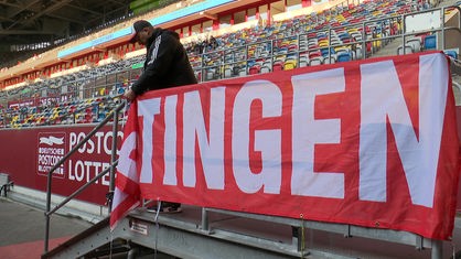 Stadionsprecher André Scheidt hängt die Ratingen-Fahne auf