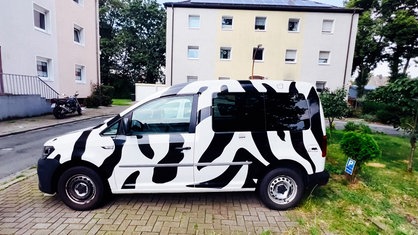 Ein Auto mit Zebra-Lackierung und schwarz-weißen Stickern.