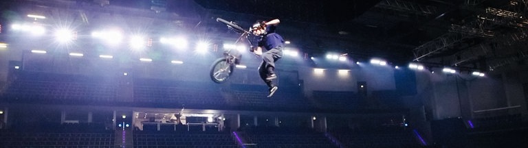 Ein junger BMX-Fahrer schwebt mit seinem Fahrrad meterweit in der Luft