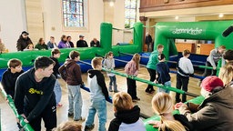 Kinder spielen in einem Menschenkicker in einer Kirche.