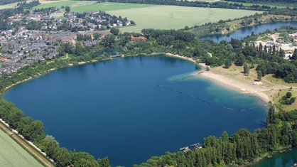 Ein Luftbild vom Escher See und den Häusern und Feldern des Veedel Köln-Esch