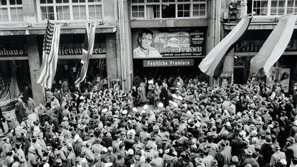 Menschen drängen sich an der Esser Lichtburg zur Filmpremiere von "Die Brücke am Kwai"