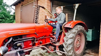 Heimatpfleger Mathis Lemke sitzt auf einem roten Traktor.