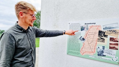 Mathis Lemke links zeigt auf eine Info-Tafel samt Dorfkarte