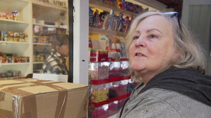 Eine Frau mit blonden Haaren steht vor einem Kiosk.