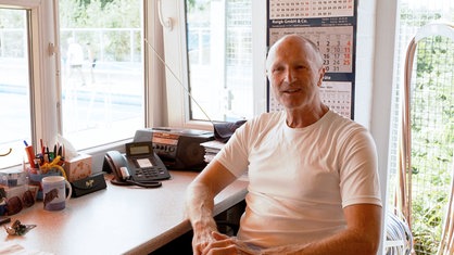 Schwimmmeister Andreas Bolte sitzt in seinem Büro an einem Schreibtisch.