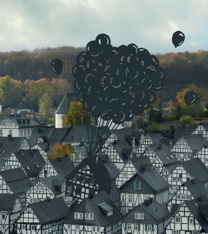 Ausschnitt aus der WDR-Kampagne des Scherenschnitt-Künstlers Paperboyo: In Freudenberg wird ein Fachwerkhaus von Luftballons nach oben gezogen