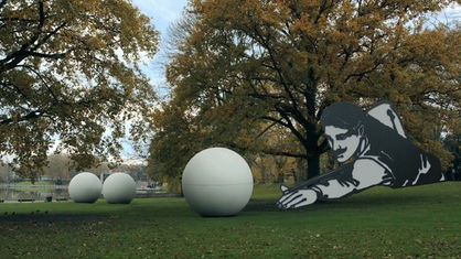 Die Giant Pool Balls in Münster: Ein Mann mit Billardqueue kommt ins Bild und richtet den Queue auf steinerne Kugeln