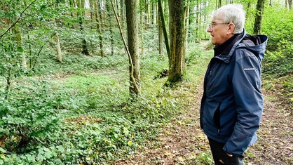 Dieter Besserer rechts im Bild. Er schaut in den Wald hinein.