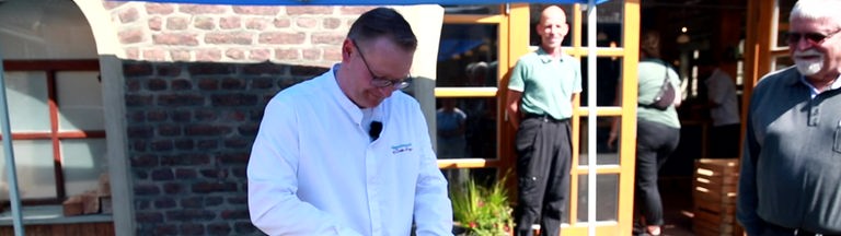 Koch Christian Krüger steht draußen an einem Grill. 