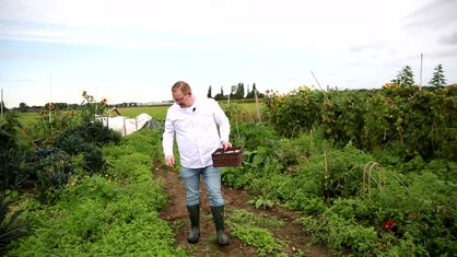 Koch Christian Krüger steht auf einem Gemüsefeld