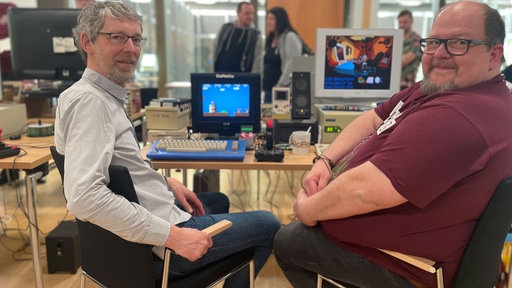 Zwei Männer sitzen vor alten Computern.