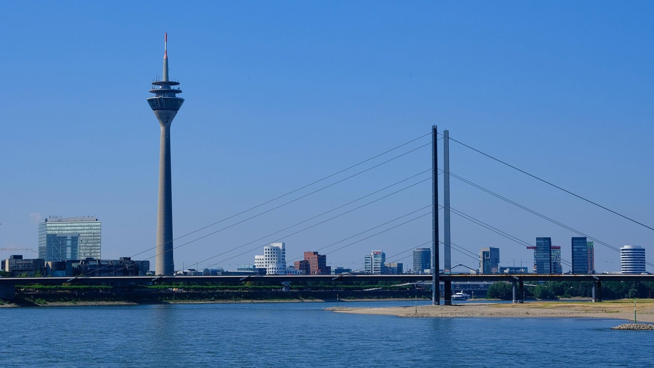 Zu sehen ist eine Brücke in Düsseldorf, die über den Rhein führt, links 