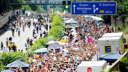 Zahlreiche Menschen tummeln sich zwischen Pavillons auf der A40 bei Essen. In der gegenüberliegenden Fahrtrichtung sind Radfahrer unterwegs.