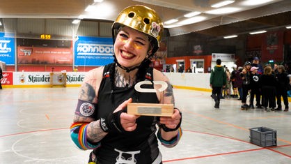 Melina Brinkmann grinst zwinkernd und hält einen Pokal in die Kamera