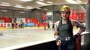 Melina Brinkmann steht an der Bande einer Hockeyarena, hinter ihr spielen Frauen Roller Derby