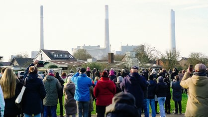 Eine Menschenmenge beobachtet und filmt die Sprengung des Kühlturms in Voerde.