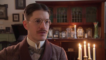 Ein wie im 19. Jahrhundert gekleideter Mann trägt Anzug und Brille
