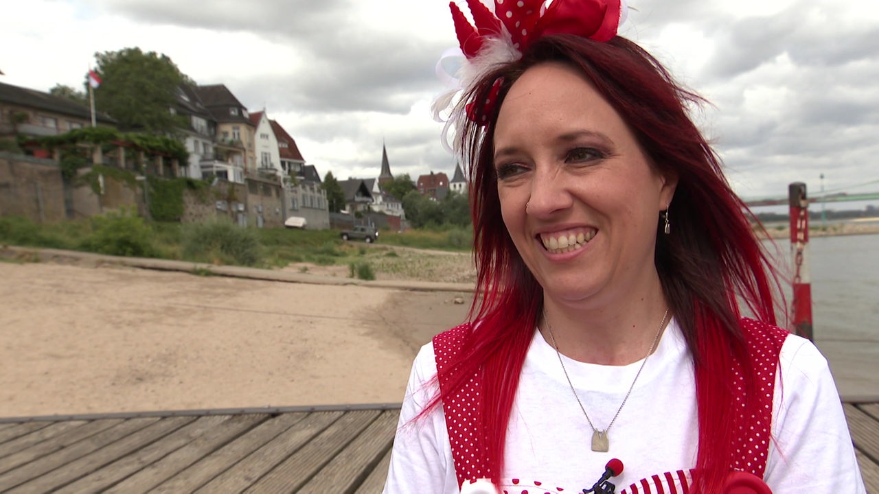 Frau mit roten Haaren und rot-weißem Karnevalskostüm lacht in Kamera