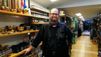 Mann mit Brille und Bart steht in einem Geschäft und lächelt in Kamera