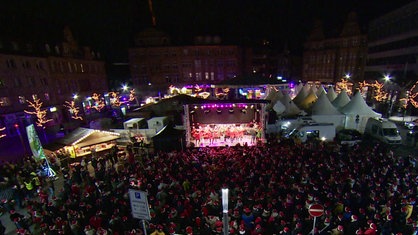 Viele Menschen tanzen mit Weihnachtsmützen vor einer Bühne