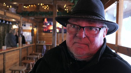 Michael Karp-Decker sitzt in einer Holzhütte auf dem Weihnachtsmarkt in Solingen