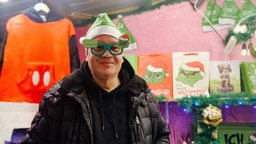 Christoph Scheiding trägt eine Weihnachtsmuffel-Mütze und eine passende Brille mit dem Grinch.