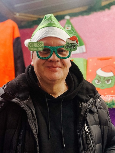 Christoph Scheiding trägt eine Weihnachtsmuffel-Mütze und eine passende Brille mit dem Grinch.