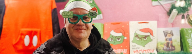 Christoph Scheiding trägt eine Weihnachtsmuffel-Mütze und eine passende Brille mit dem Grinch.