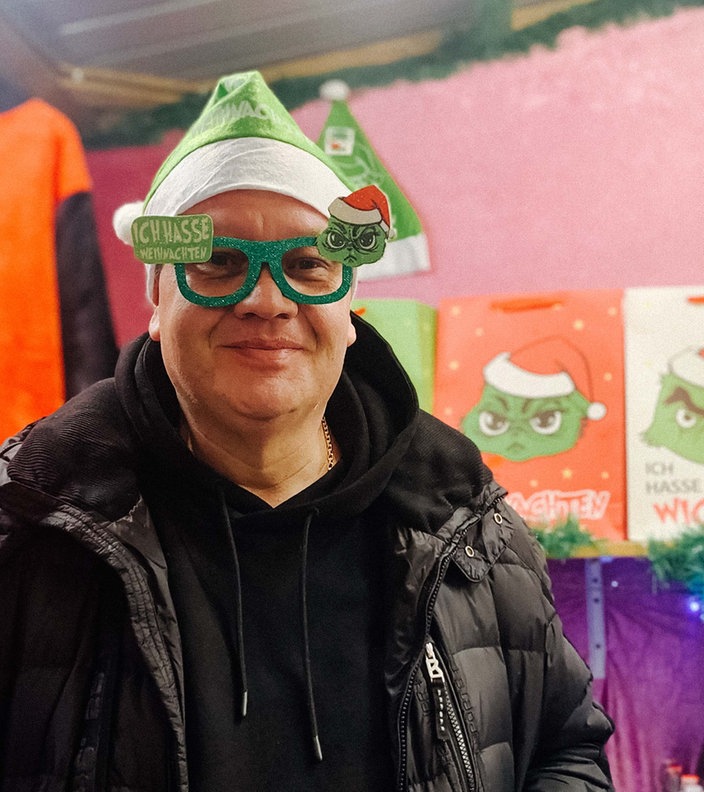 Christoph Scheiding trägt eine Weihnachtsmuffel-Mütze und eine passende Brille mit dem Grinch.