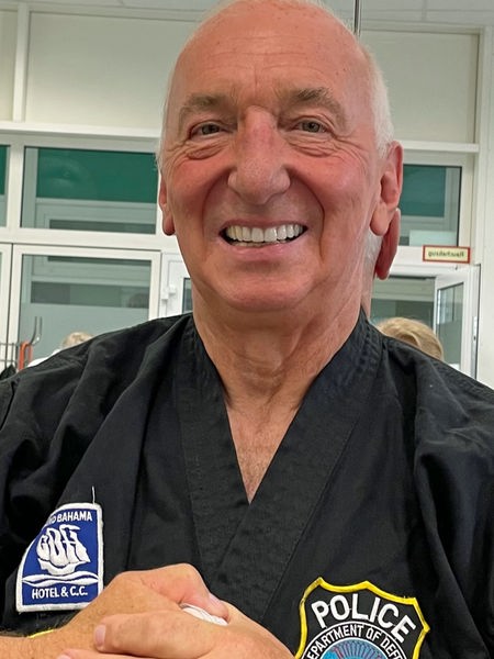 Wolfgang Ufer, ein älterer Mann, der in die Kamera lächelt und einen schwarzen Karateanzug trägt