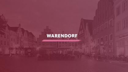Marktplatz der historischen Altstadt in der Abenddämmerung. Darauf der Schriftzug "Warendorf".