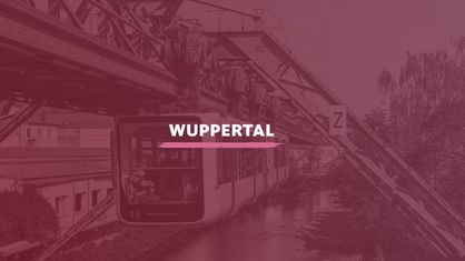 Blick auf die Schwebebahn über der Wupper am Stadtteil Arrenberg. Darauf der Schriftzug "Wuppertal".