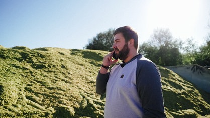 Disponent Tobias Löhr steht vor einem Berg Maissilage