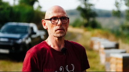 Ein Mann mit rotem T-Shirt und Brille.