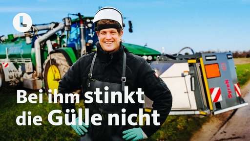 Ein Landwirt steht vor einem Traktor, der Gülle ausfährt