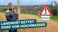 Fotocollage: Landwirt Gerd Möhren hält Miscanthus-Schilf hoch, im Hintergrund das Dorf Bengen. Neben ihm ein Warnschild mit der Aufschrift "Hochwasser". Darauf der Schriftzug "Landwirt rettet Dorf vor Hochwasser".