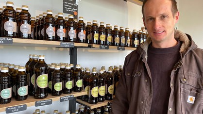 Landwirt Andreas Becker steht im Hofladen vor seinem selbstgepresstem Hanföl